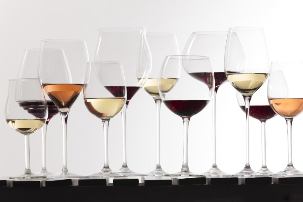 A variety of different types of wine glasses containing red, white, and rosé wines arranged on a table.