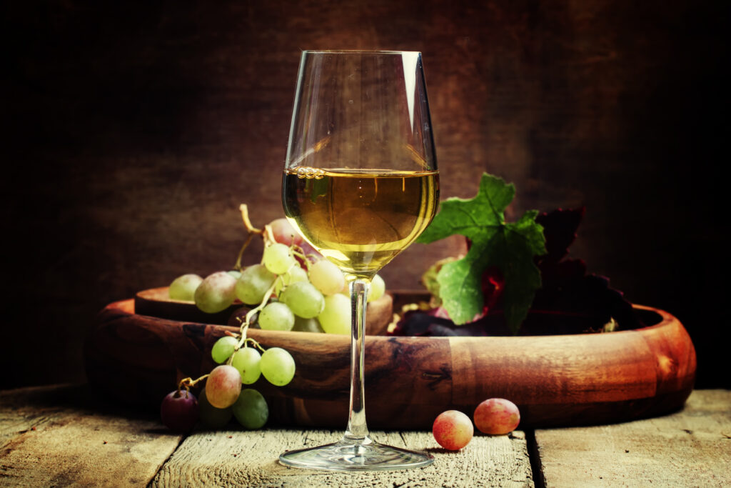 A glass of Eiswein (icewine) in front of a bowl of grapes.