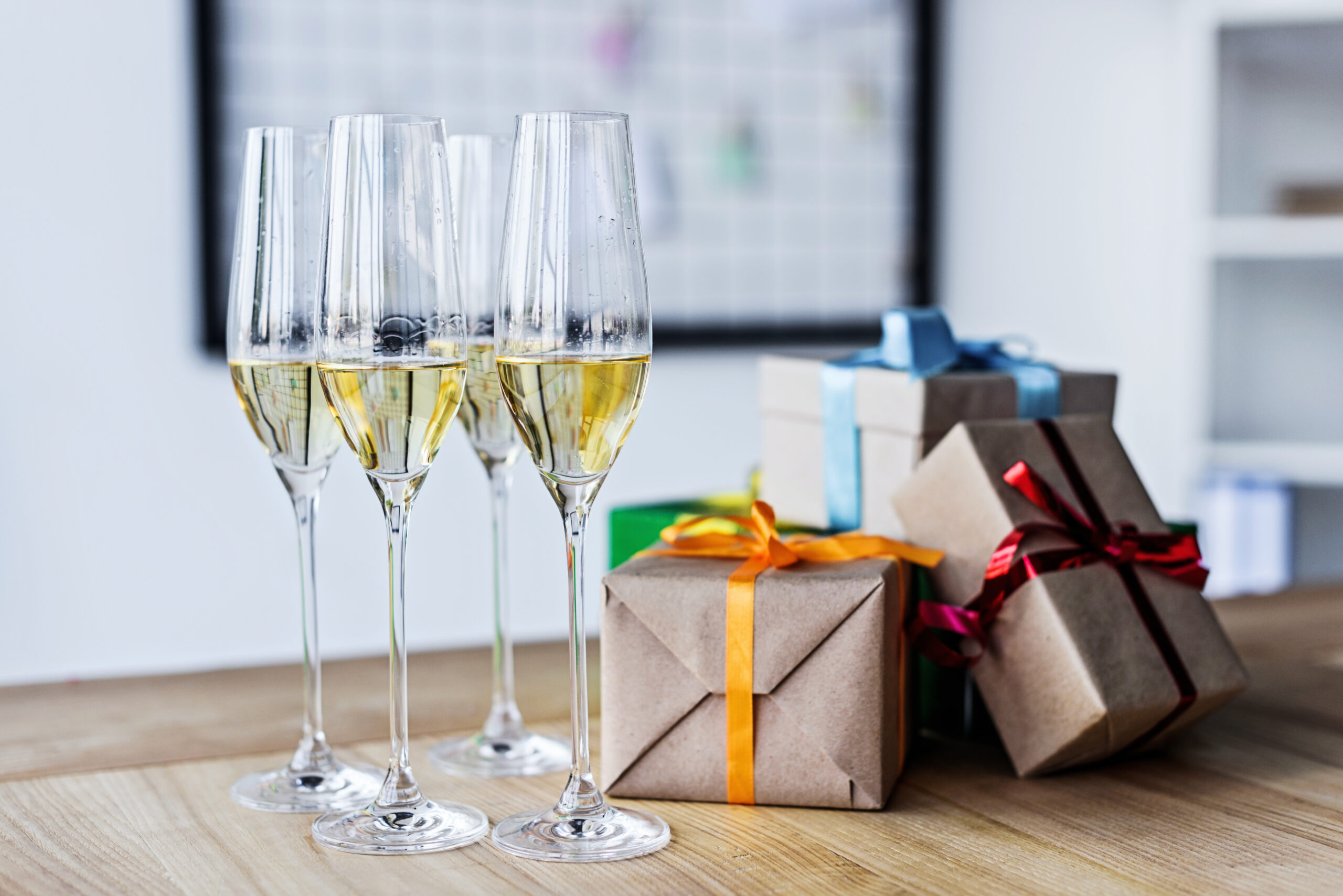 Glasses of wine next to wrapped gift boxes.