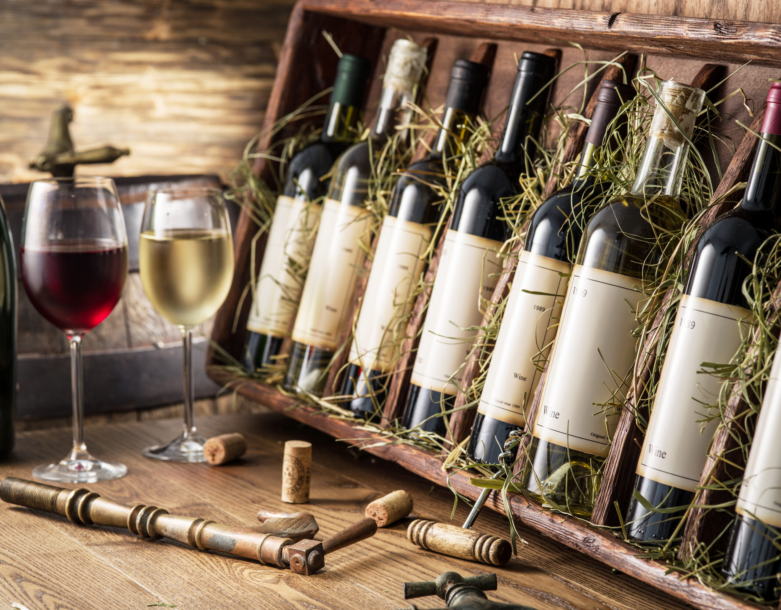 Glasses of red and white wine, in front of a selection of bottles of wine boxed up for shipping.