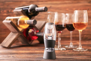 Wine aerator in front of a rack of wine bottles and glasses of red and rosé wine.