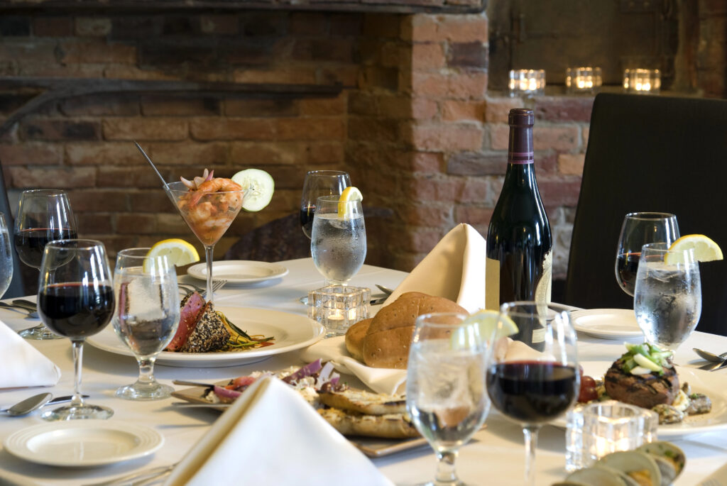 A wine bottle and wine glasses on a table with various foods.