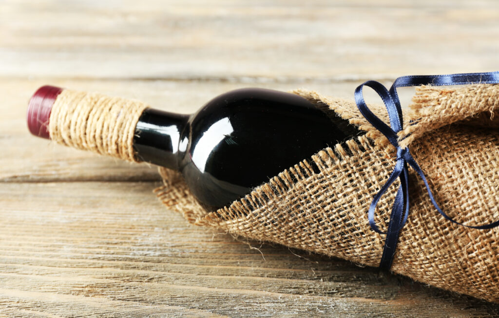 A bottle of wine wrapped in burlap and twine, to be given as a gift.