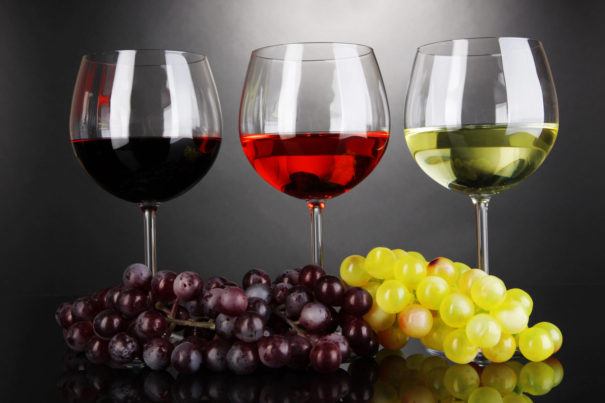 Glasses of red, white, and rose wine with grapes.