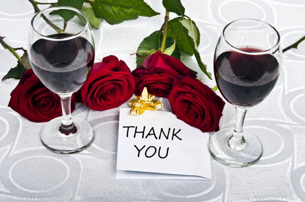 Glasses of wine and roses, with a note saying “Thank You.”