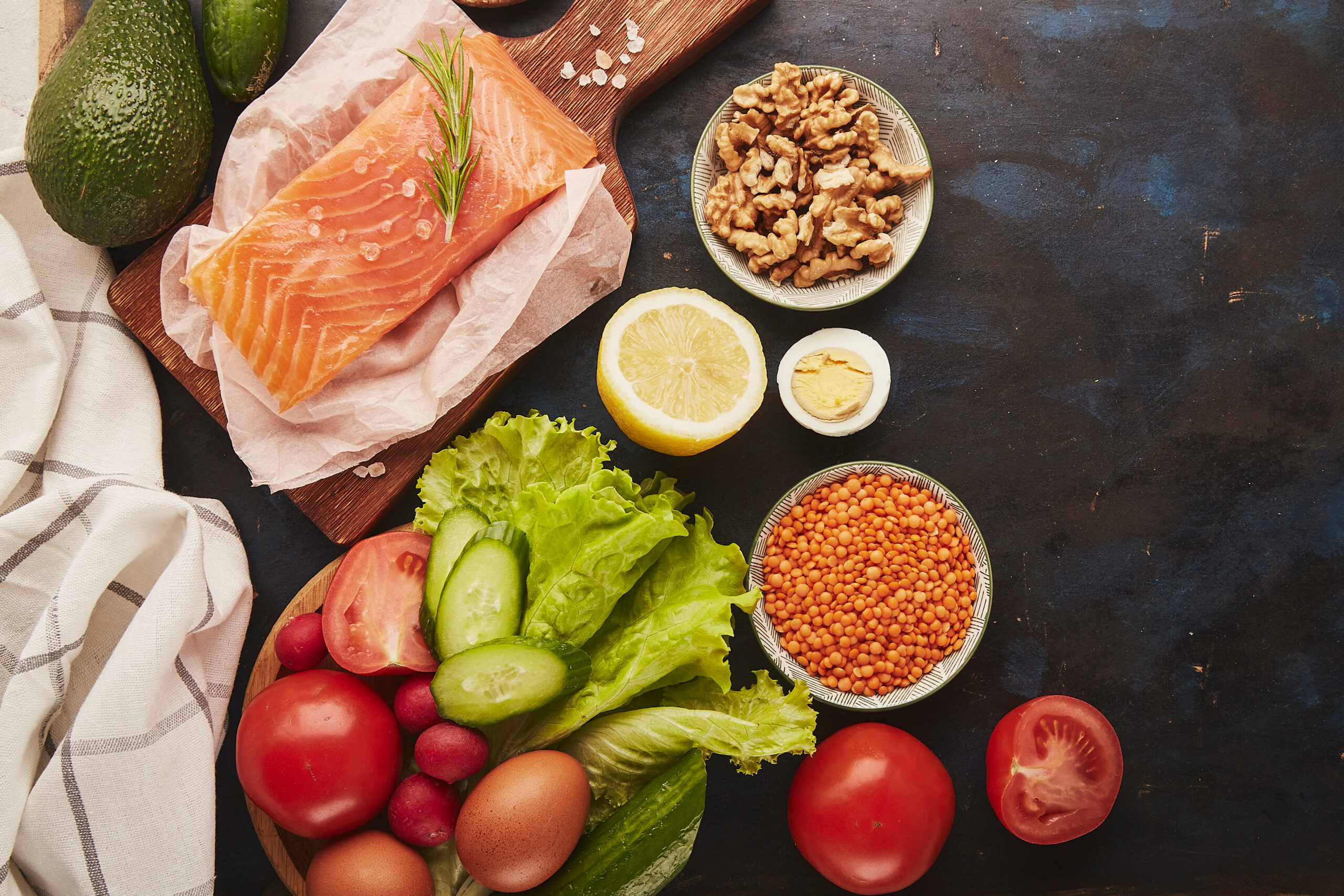 An assortment of healthy foods and ingredients, including salmon, tomatoes, and walnuts.